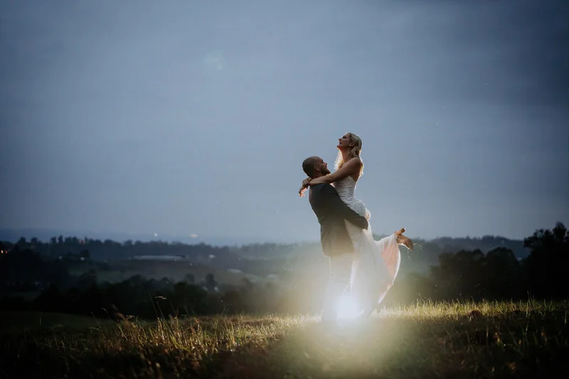 Bride and groom in a night time embrace on the hillside at Loxley on Bellbird Hill with Blue Mountains views behind them