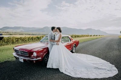 Groom Andrew kissing bride Rebecca over a retro car outside Enzo Hunter Valley at sunset