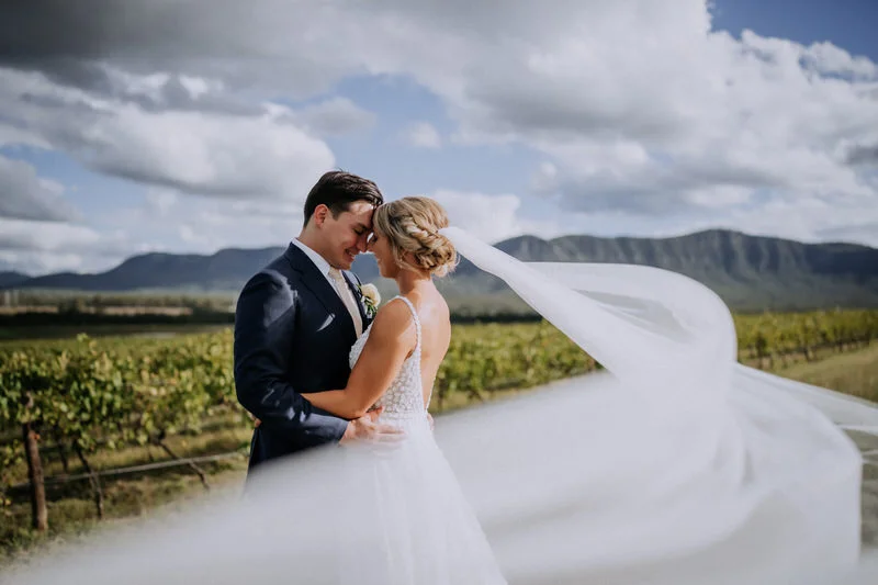 Bride and groom sharing an intimate moment just outside Enzo Hunter Valley with vineyard views behind them