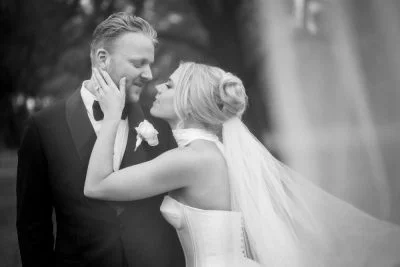 Black & white portrait of bride & groom with the veil partially draping them, in the vineyards at Enzo Weddings Hunter Valley